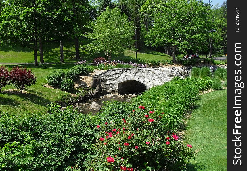 A scenic garden with a small creek and a bridge.