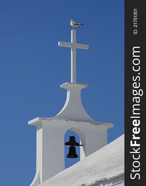 Seagull on the cross of a Greek chapel or church
