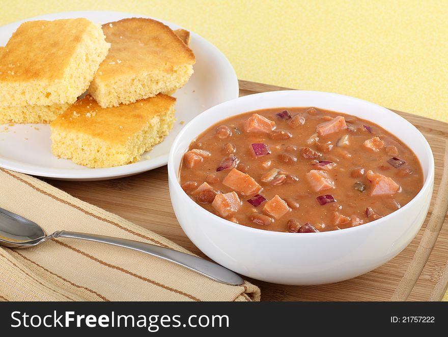 Bowl of ham and bean soup with corn bread on the side