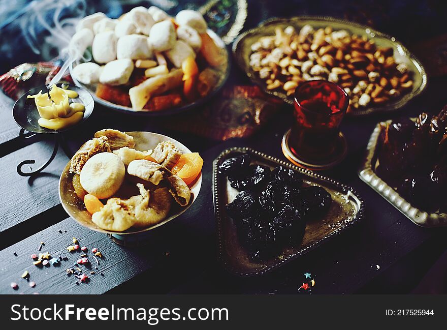 Eastern sweets. Dried fruits. Nuts. Haze from an extinguished candle.