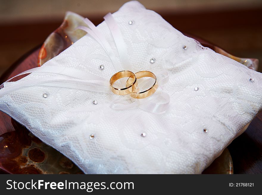 Gold wedding rings on white pillow