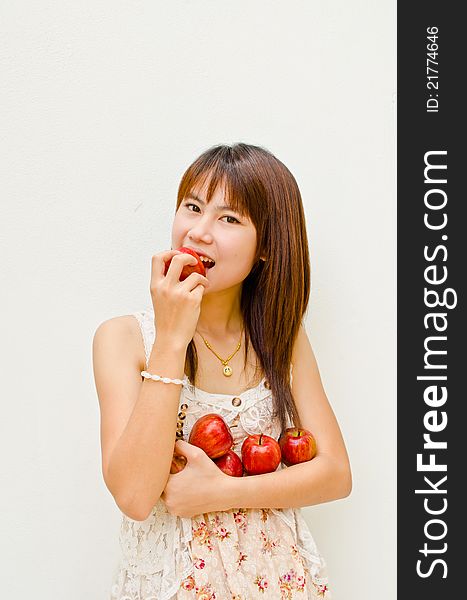 Asain girl hold apples in her arm and eating apple on white background. Asain girl hold apples in her arm and eating apple on white background