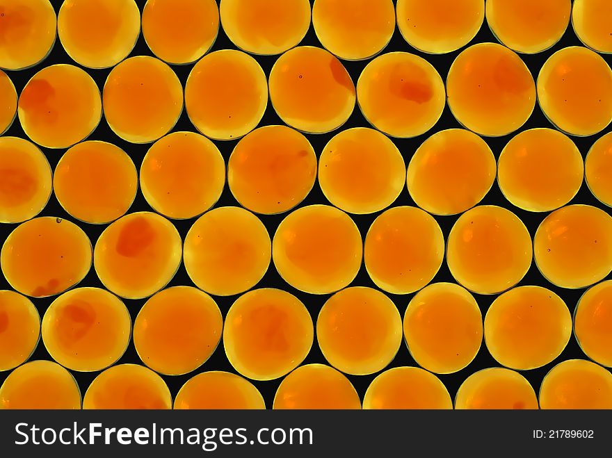 Close-up of orange glass gems on black background.