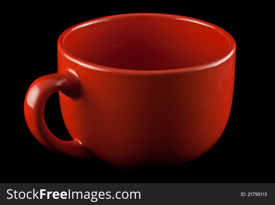 Red porcelain cup on a black background.