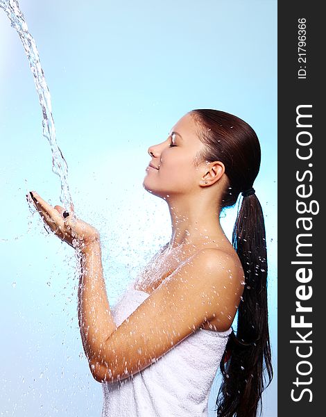 Beautiful woman under splash of water against blue background