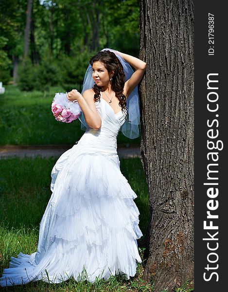 Elegant bride standing about tree in park