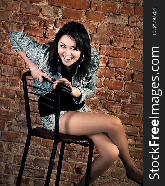 Smiling young woman sitting on a brick wall background