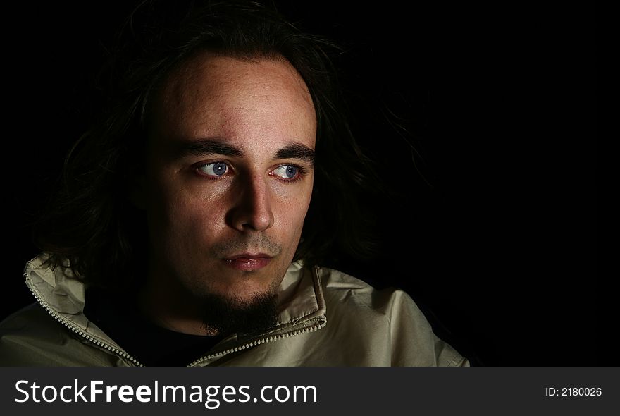 Long haired man with blue eye looking to the side with some shadow on his face to give moody feel. Long haired man with blue eye looking to the side with some shadow on his face to give moody feel