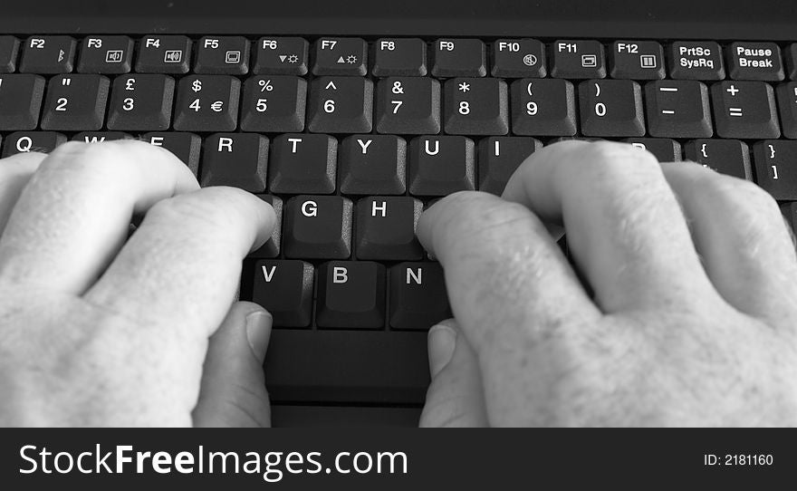 Close-up of businessman's hands typing on laptop's keyboard. Black and white image.