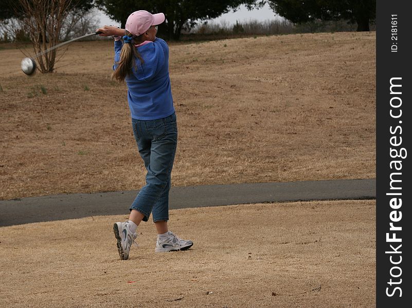 Woman teeing off at golf course. Woman teeing off at golf course