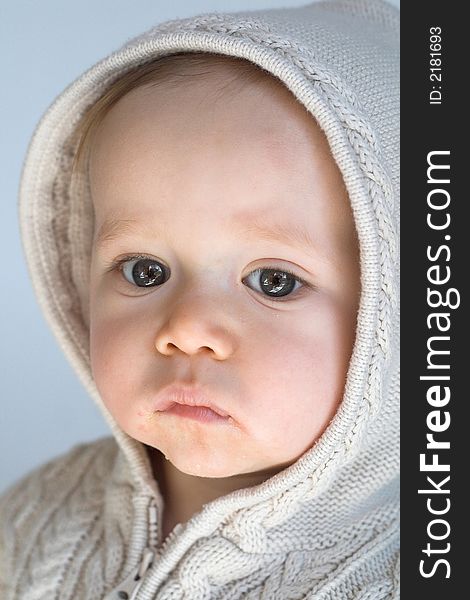 Image of cute baby wearing a hooded sweater, sitting in front of a white background. Image of cute baby wearing a hooded sweater, sitting in front of a white background