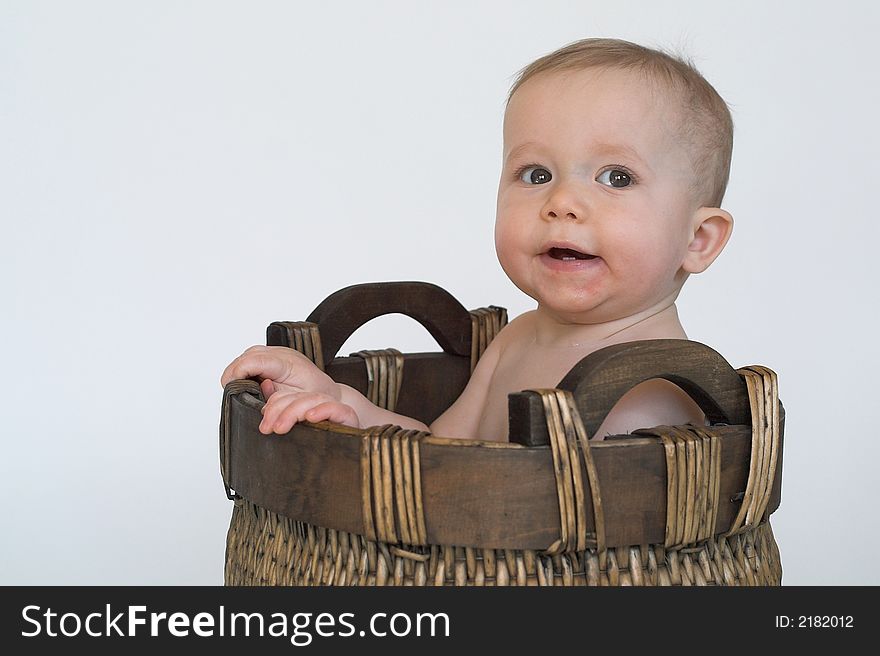 Image of cute, smiling baby sitting in a woven basket. Image of cute, smiling baby sitting in a woven basket