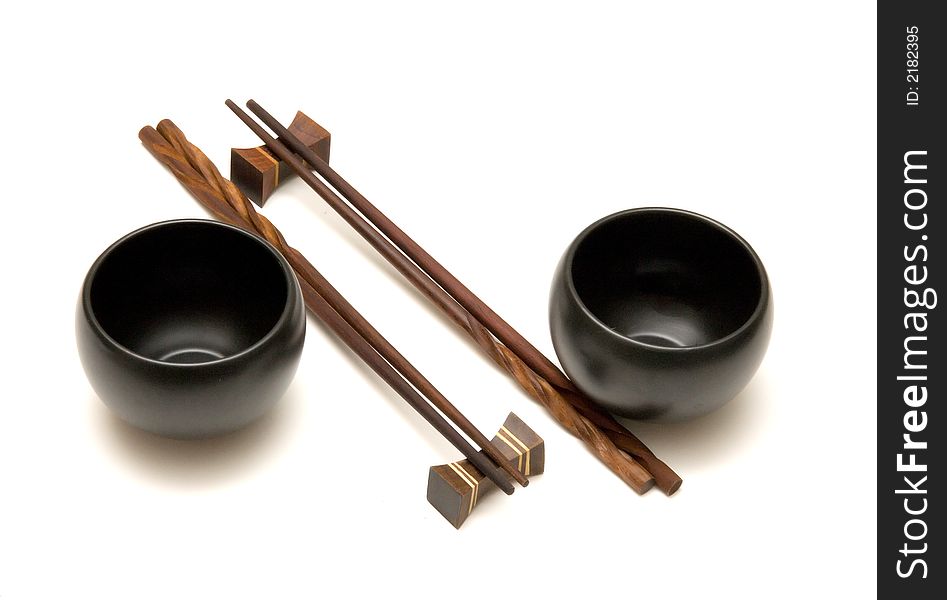 Wooden chopsticks and black tea cups over white. Wooden chopsticks and black tea cups over white.