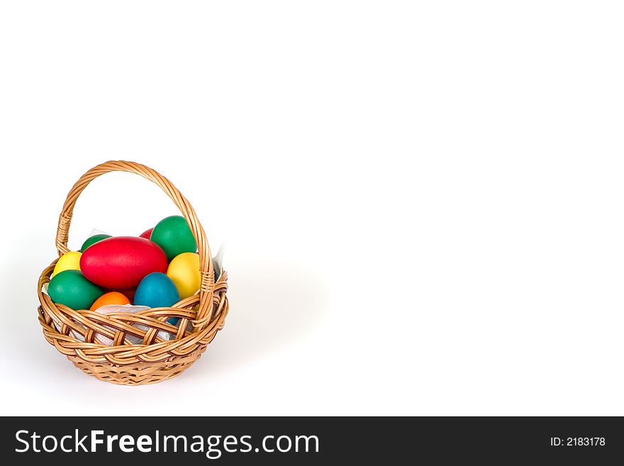 A woven basket with multi colored eggs over white background. A woven basket with multi colored eggs over white background