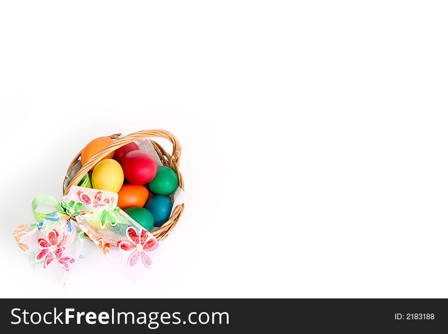 A woven basket with bow and multi colored eggs inside, over white background. A woven basket with bow and multi colored eggs inside, over white background