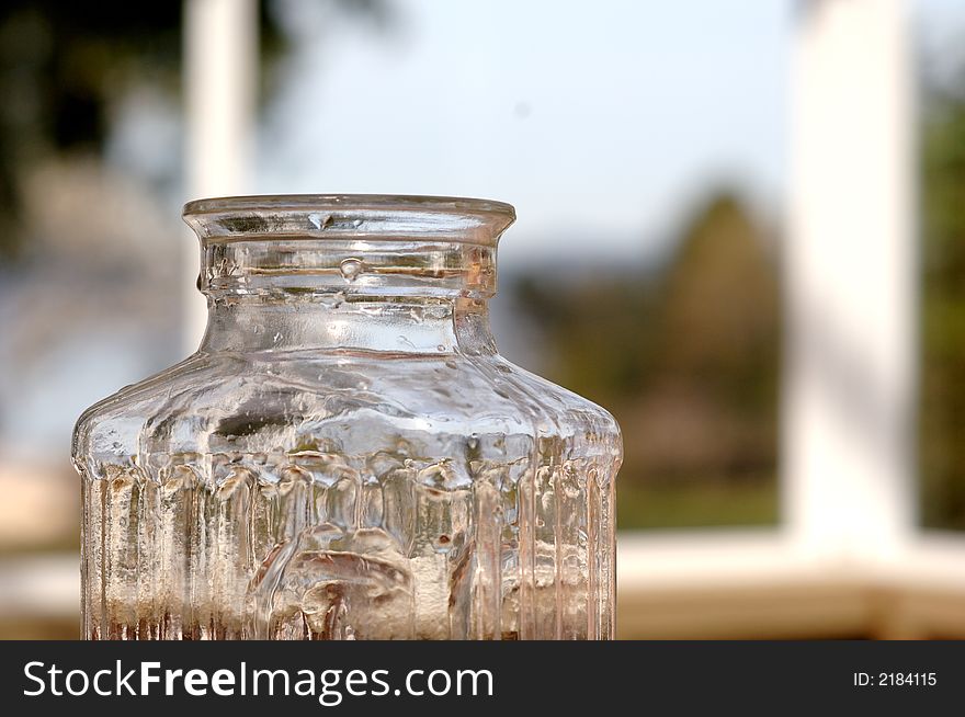 Top half of a glass pitcher with windows in the background