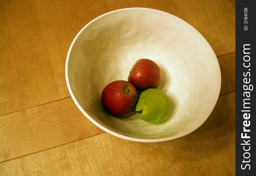 A bowl of fruit on a solid wood table. A bowl of fruit on a solid wood table