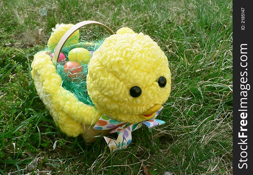 Photo of baby chick styled Easter basket filled with plastic eggs on grass lawn. Photo of baby chick styled Easter basket filled with plastic eggs on grass lawn