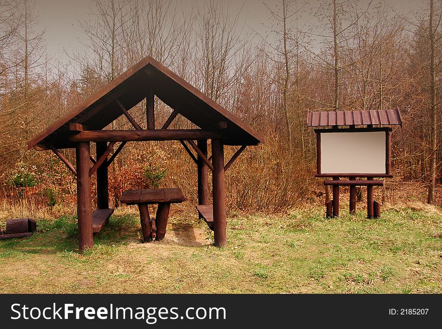 Brown gazebo in the forest with bright board on right - just add your text