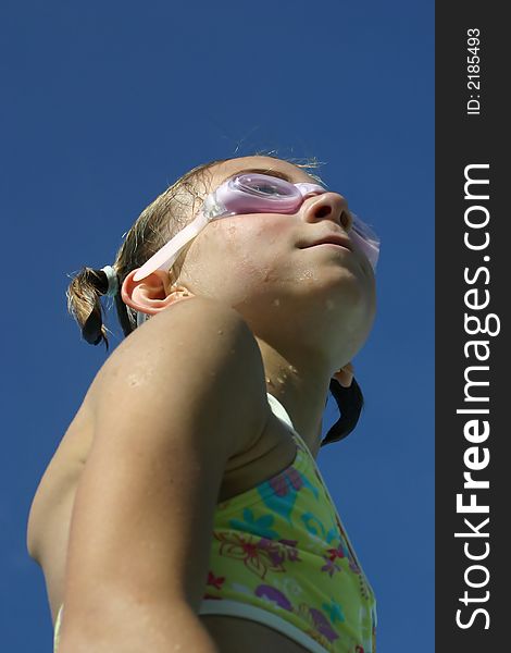 Girl in swimsuit wearing swimming goggles looking up. Girl in swimsuit wearing swimming goggles looking up