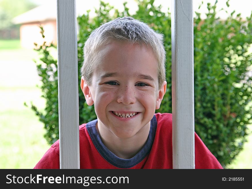 A Boy smiling between wooden railings