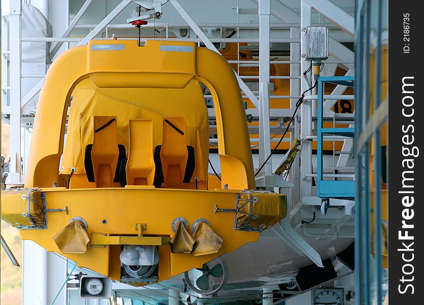 A bright yellow rescue boat hanging in a rack