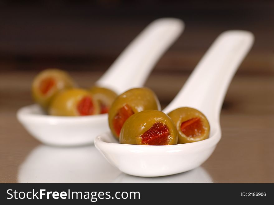 Low view of green stuffed olives in two white spoons