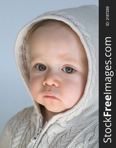 Image of cute baby wearing a hooded sweater, sitting in front of a white background. Image of cute baby wearing a hooded sweater, sitting in front of a white background