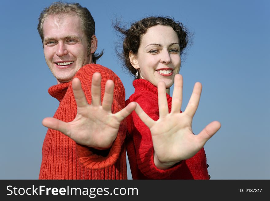 Couple with fingers against sky