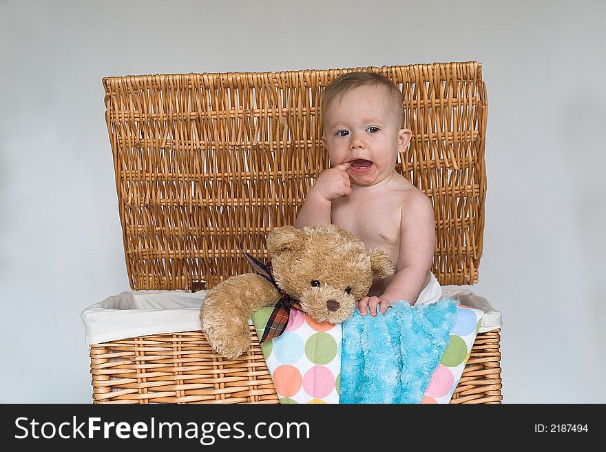 Image of cute baby and teddy bear peeking out of a wicker trunk