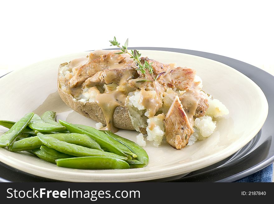 Great for lunch or dinner, a baked potato topped with pork tenderloin and country gravy with a side of butter coated sugar snap peas and a sprig of thyme. Great for lunch or dinner, a baked potato topped with pork tenderloin and country gravy with a side of butter coated sugar snap peas and a sprig of thyme.