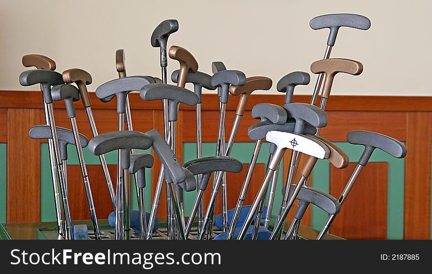 Golf putters sticking out of a rack
