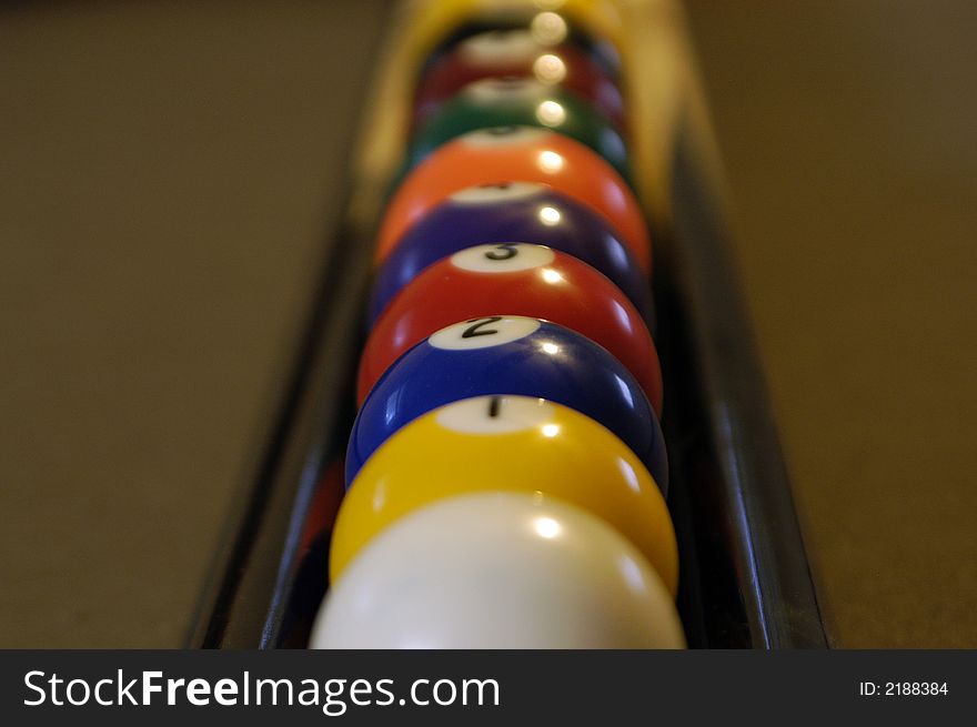 A set of pool balls sitting on some pool sticks.