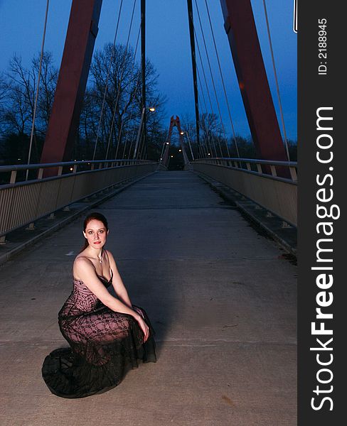 Tall female fashion model poses on a walkway at twilight. Tall female fashion model poses on a walkway at twilight.