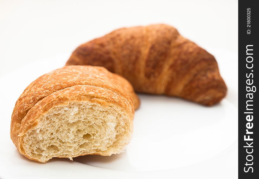 French croissants (one bitten) on a white plate.