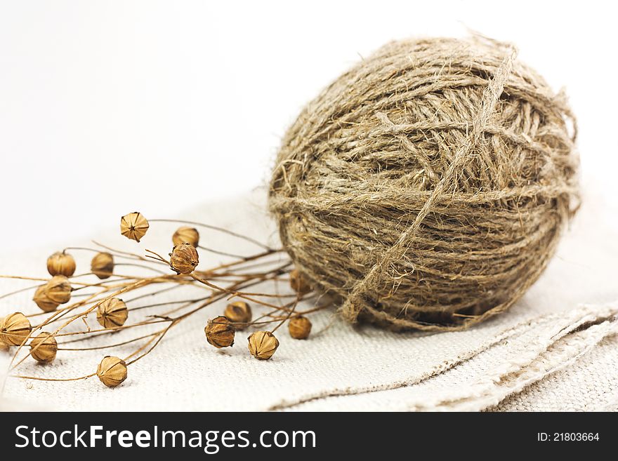 A ball of coarse flax yarn and flax are on linen. A ball of coarse flax yarn and flax are on linen