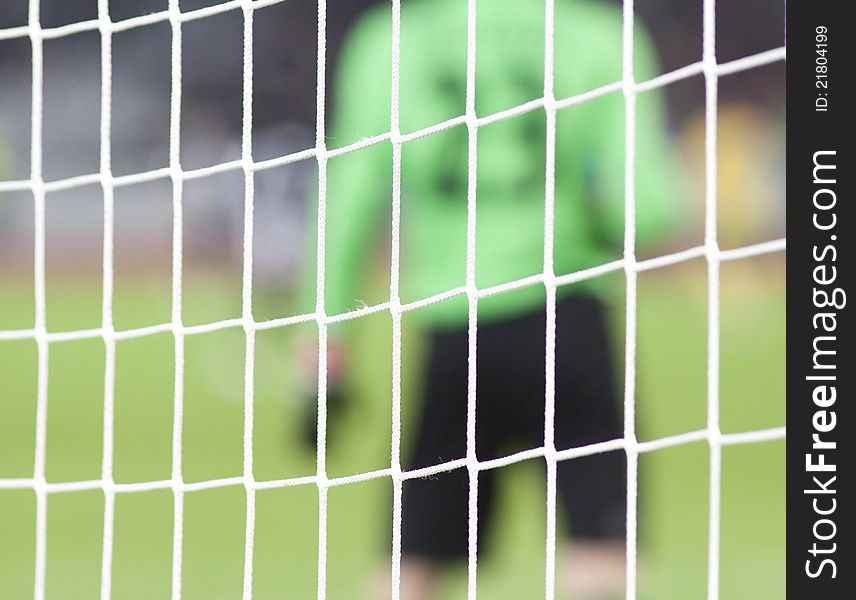 Goalkeeper blurred behind soccer net