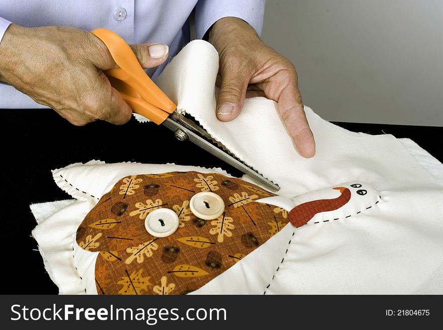 A woman using pinking shears to create a Thanksgiving turkey decoration.