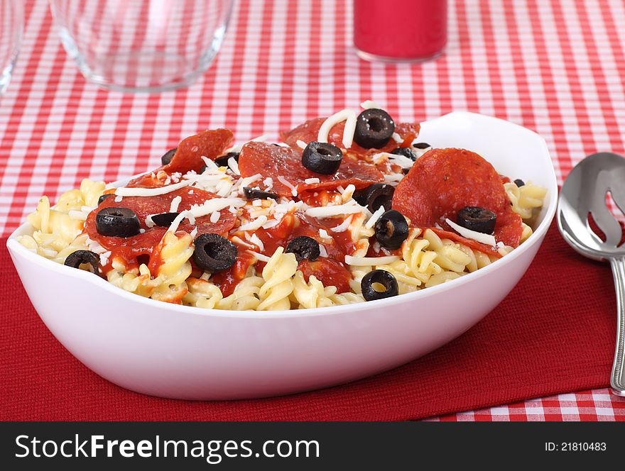 Bowl of pasta noodles with pepperoni and black olives. Bowl of pasta noodles with pepperoni and black olives