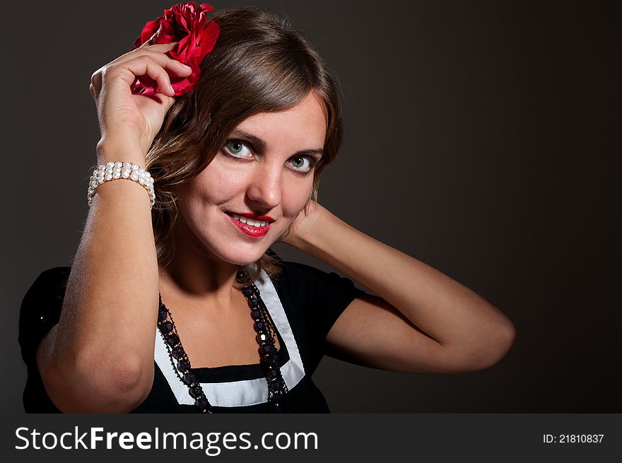 Beautiful retro woman with red flower in hair in low key high contrast