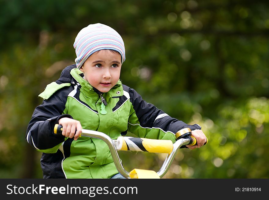 Little boy riding bike outdoors in autumn forest