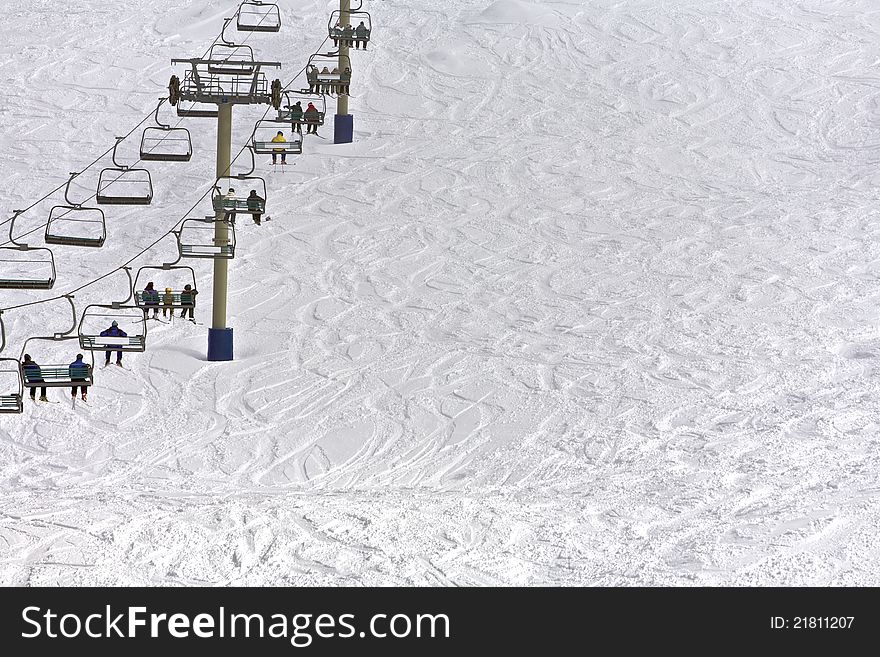 Snow resort with skiers sitting on a chairlift with snow background. Snow resort with skiers sitting on a chairlift with snow background
