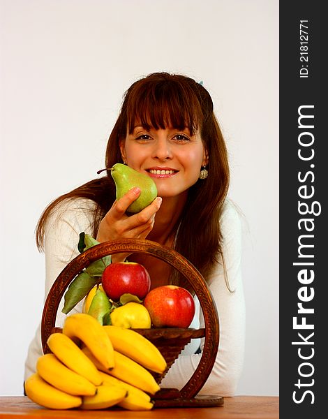 A smiling beautiful woman with different fruits (banana,apple,pear,cydonia) holding a pear isolated on a white background. A smiling beautiful woman with different fruits (banana,apple,pear,cydonia) holding a pear isolated on a white background