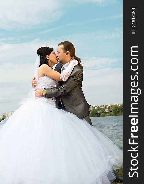 Happy bride and groom against blue sky outdoor