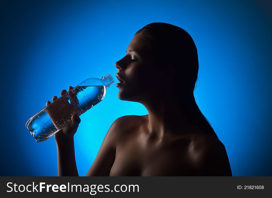 Beautiful woman holding a bottle of water on a blue background
