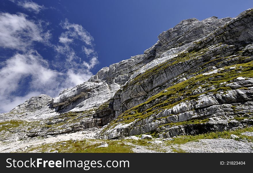 Detail of a rock in Slovenian Alps with blue sky and white cloud. Detail of a rock in Slovenian Alps with blue sky and white cloud