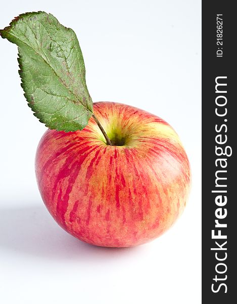 Red apple with green leaf photographed against a white background. Red apple with green leaf photographed against a white background