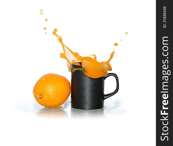 Freshness orange near black mug with splashing juice. Isolated on white with clipping path. Freshness orange near black mug with splashing juice. Isolated on white with clipping path