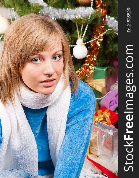 A young woman sits near a new-year tree. A young woman sits near a new-year tree