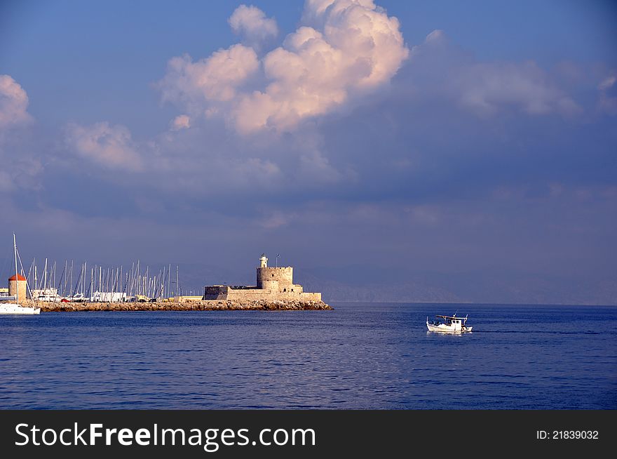 The imagw shows a traditional fishing boat arriving at the ancient walled harbour of rhodes, greece. The imagw shows a traditional fishing boat arriving at the ancient walled harbour of rhodes, greece